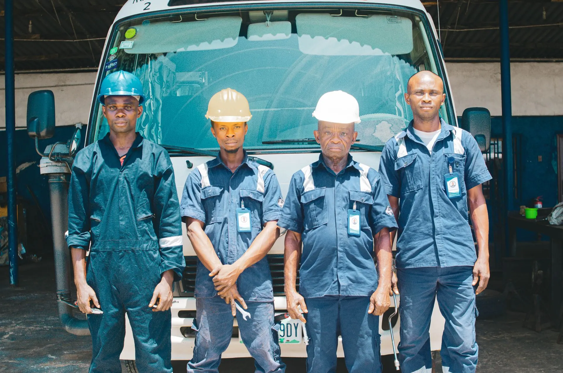 A crew in blue coveralls and hard hats standing in front of a work truck
