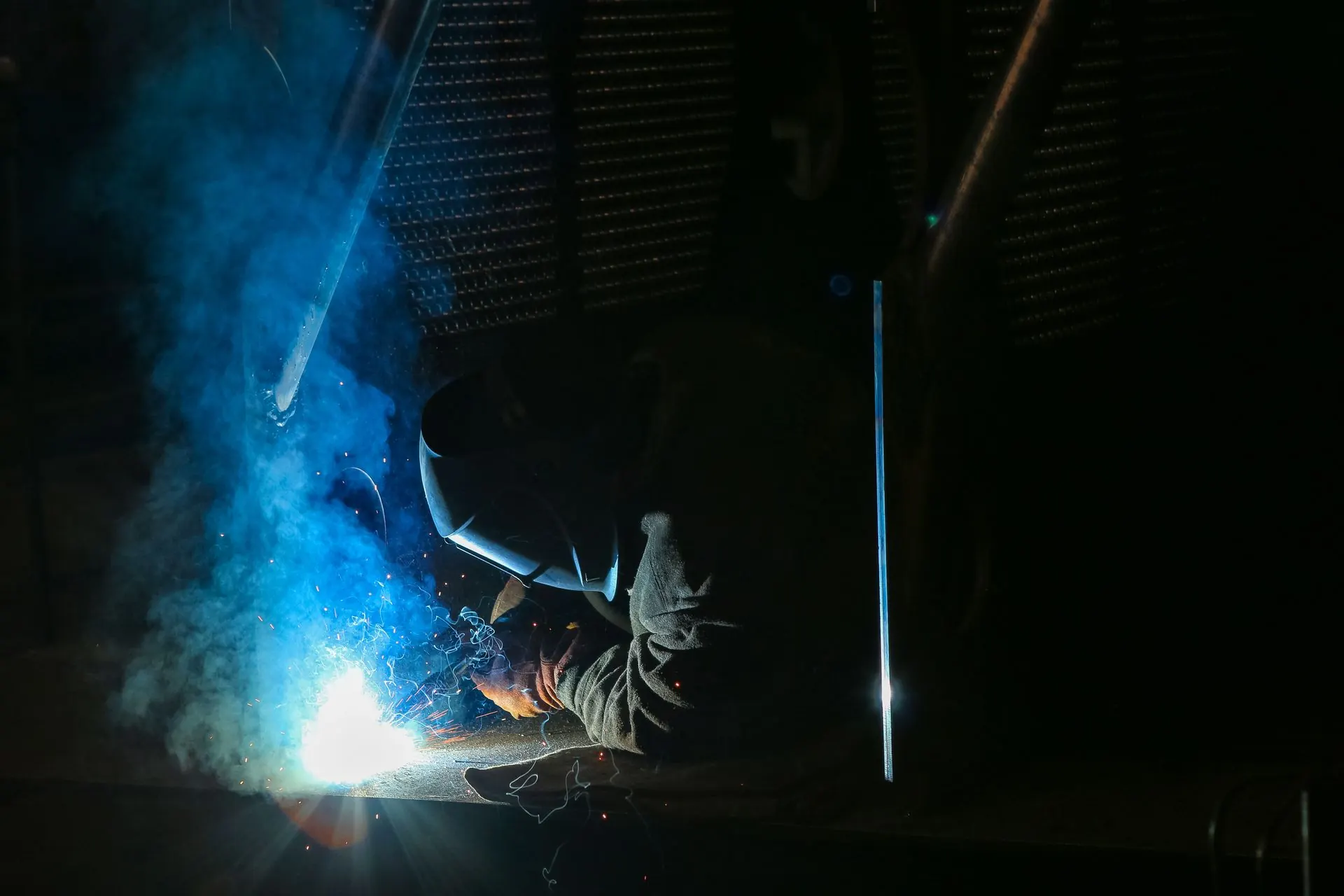 A welder at work under blue arc light